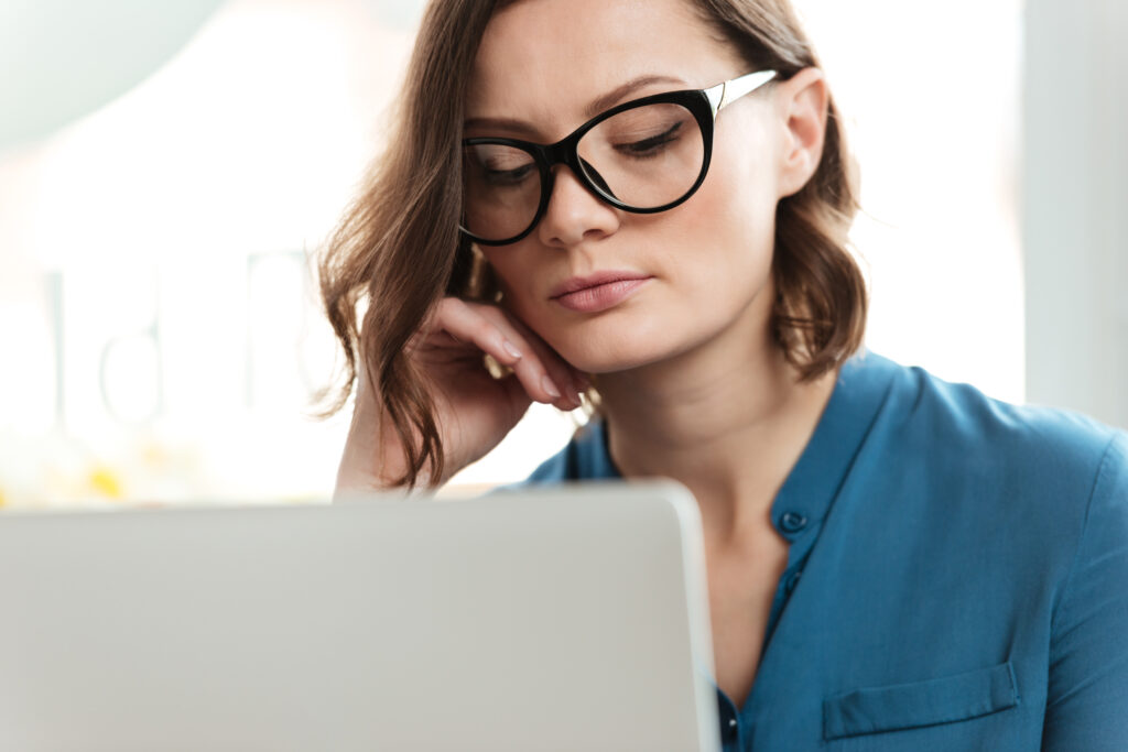 Een vrouw draagt blue light glasses terwijl ze op een laptop werkt, als voorbeeld van hoe de brillen ogen beschermen tegen blauw licht